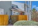 View of the townhome's wood fence and exterior, highlighting the tidy landscaping and proximity to trees at 5128 Buckingham Rd, Boulder, CO 80301