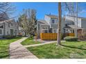 Exterior of a townhome featuring a well-kept lawn, neat landscaping, and a wooden privacy fence at 5128 Buckingham Rd, Boulder, CO 80301