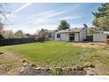 Spacious backyard featuring a lush lawn, privacy fence, and mature trees under a bright sky at 2476 Sunset Dr, Longmont, CO 80501