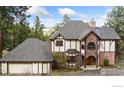 Stunning Tudor-style home with brick accents, a side-entry garage, and lush landscaping at 24771 Westridge Rd, Golden, CO 80403
