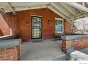 Inviting covered front porch with brick accents, outdoor seating, and a 'hello' welcome mat at 3059 N York St, Denver, CO 80205