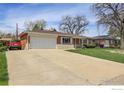 Ranch-style home with a large driveway, two-car garage, brick facade, and well-maintained lawn at 375 Kohl St, Broomfield, CO 80020