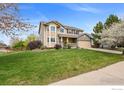 Well-maintained two-story home with green lawn, mature trees, and a stone accent two car garage at 4833 Falcon Dr, Frederick, CO 80504