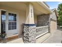 Inviting front porch with stone pillars, decorative railing, and a view of the stone accent garage at 4833 Falcon Dr, Frederick, CO 80504