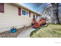 A side view shows the home's entrance with a porch and a walkway surrounded by flowers and greenery at 720 Bunyan Ave, Berthoud, CO 80513