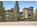 Apartment building with balconies surrounded by lush evergreens under a blue sky at 755 Columbine Rd # 303, Breckenridge, CO 80424