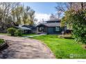 Inviting home with lush green lawn, garden beds, and a covered carport at 7800 Hygiene Rd, Longmont, CO 80503