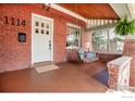 Inviting front porch with swing, offering a relaxing outdoor space with brick accents at 1114 5Th Ave, Longmont, CO 80501