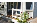 Inviting front porch with wood floors, white railings, and a garden with beautiful red roses at 1696 Bain Dr, Erie, CO 80516
