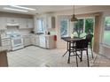 Bright kitchen with white appliances, tile floors, table and chairs, and a sliding door to the backyard at 1696 Bain Dr, Erie, CO 80516