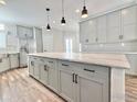 Bright kitchen featuring a large marble island, gray cabinets, stainless steel appliances and wood flooring at 17910 County Road 38, Platteville, CO 80651