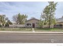 Quaint single-story home with a fenced front yard and mature trees at 214 2Nd St, Frederick, CO 80530
