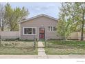 Quaint single-story home with a fenced front yard and mature trees at 214 2Nd St, Frederick, CO 80530