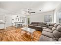 Spacious living room with hardwood floors, a ceiling fan, and a comfortable gray sectional at 21562 E 47Th Ave, Denver, CO 80249