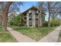 Charming exterior view with balconies, large windows, mature trees and lush green lawn at 400 Emery St # 104, Longmont, CO 80501