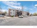 Apartment complex with gray facade, multiple balconies, brick accents, and ample parking spaces for residents and visitors at 6385 Oak St # 301, Arvada, CO 80004