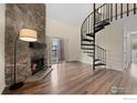 Living room with stone fireplace, hardwood floors, spiral staircase, and sliding glass door to the balcony at 6385 Oak St # 301, Arvada, CO 80004