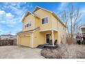 Inviting two-story yellow home with a cozy front porch and an attached one car garage at 740 Boxwood Ln, Longmont, CO 80503