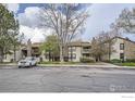 A multi-unit building featuring neutral siding and stone accents, surrounded by mature trees and ample parking at 7720 W 87Th Dr # N, Arvada, CO 80005