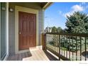 Balcony featuring wood decking and metal railings with views of trees and a nearby home at 804 Summer Hawk Dr # 11208, Longmont, CO 80504