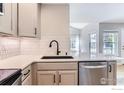 Bright kitchen featuring a stainless steel dishwasher, black faucet, and gray cabinets at 827 Snowberry St, Longmont, CO 80503