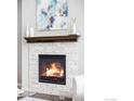 Close up of a stone fireplace with wood mantle in a well lit living room at 8346 Wilkerson Ct, Arvada, CO 80007