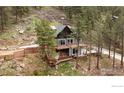Exterior of the A-frame house showing decks, stairs, and mature trees at 93 Pine Needle Rd, Boulder, CO 80304