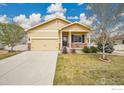 Inviting one-story home with a well-kept lawn, two-car garage, and a cozy front porch sitting under a partly cloudy blue sky at 11166 Charles St, Firestone, CO 80504