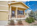 Inviting front porch with brick accents, a cozy seating area, a storm door, and manicured landscaping and healthy green bushes at 11166 Charles St, Firestone, CO 80504