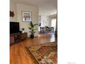 Open-concept living room flowing into the dining area with hardwood floors and stylish decor at 13873 Legend Way # 103, Broomfield, CO 80023