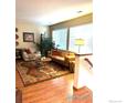Cozy living room with hardwood floors, large windows providing natural light, and comfortable seating arrangements at 13873 Legend Way # 103, Broomfield, CO 80023