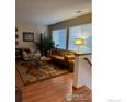 Cozy living room with hardwood floors, large windows, and comfortable seating area at 13873 Legend Way # 103, Broomfield, CO 80023