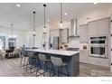 Modern kitchen featuring an island with seating, stainless steel appliances, and stylish pendant lighting at 1641 Poplar Dr, Erie, CO 80516