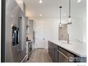 Bright kitchen featuring stainless steel appliances, pendant lights, white countertops, and modern gray cabinetry at 1641 Poplar Dr, Erie, CO 80516