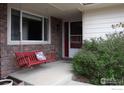 Inviting front porch with a red porch swing, brick accents, and access to the main entrance at 226 S 3Rd St, Berthoud, CO 80513