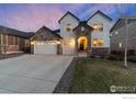 Stunning two-story home with stone accents, three-car garage, and a well-manicured lawn at dusk at 228 Horizon Ave, Erie, CO 80516