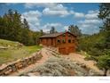 Charming log cabin-style home with a stone pathway and two-car garage nestled in a serene forest setting at 310 Wendelyn Way, Boulder, CO 80302