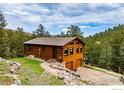 Quaint log cabin home with a two-car garage and stone-lined walkway in a wooded setting at 310 Wendelyn Way, Boulder, CO 80302