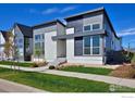 Contemporary home featuring a gray and white exterior, a well-manicured lawn, and a sidewalk at 603 Mountain Dr, Longmont, CO 80503