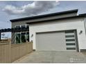 Attached garage with sleek door, accompanied by pergola and fenced yard at 603 Mountain Dr, Longmont, CO 80503