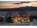 Exterior view of home at dusk with holiday lighting and a picturesque mountain backdrop at 6224 Trevarton Dr, Longmont, CO 80503