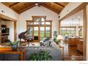 Spacious living room featuring a vaulted ceiling, hardwood floors, grand piano, and great views at 6224 Trevarton Dr, Longmont, CO 80503