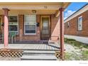 Inviting front porch with wooden deck, brick supports, and natural light exposure at 72 N Pennsylvania St, Denver, CO 80203