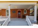 Charming covered front porch with brick facade, white columns and railings, and a bright red door at 838 University Ave, Boulder, CO 80302
