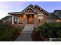 Inviting home featuring stone accents, a covered entry, and a well-manicured front yard at 8392 Niwot Meadow Farm Rd, Niwot, CO 80503