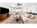 Bright living room featuring a large sectional sofa, modern entertainment center, and scenic backyard views at 840 Clover Loop, Lafayette, CO 80026