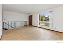Inviting living area with hardwood floors, a large window, and an open staircase at 9 Seattle Ln, Longmont, CO 80501
