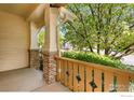 Covered front porch with decorative brick pillars and wooden railing at 1038 Village Cir, Erie, CO 80516