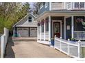 Detailed exterior showcasing a two-car garage and a covered porch with hanging plants and white picket fence at 1121 Lincoln Ave, Louisville, CO 80027