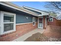 Inviting front entrance with brick accents and a charming storm door at 130 Ash St, Hudson, CO 80642